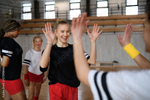 Group of young and old cheerful women  floorball team players  in gym cebrating victory.