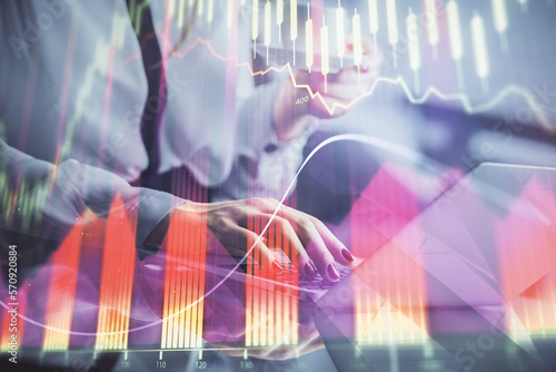 Double exposure of businesswoman hands typing on computer and financial graph hologram drawing. Stock market analysis concept.