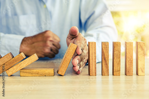 Obraz na płótnie Close-up hand prevent wooden block not falling domino concepts of financial risk management and strategic planning and business challenge plan or safety insurance