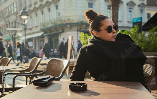 Belgrade, Serbia. February 11th, 2023. Girl sitting outside a restaurant in Belgrade on a sunny but cold afternoon.