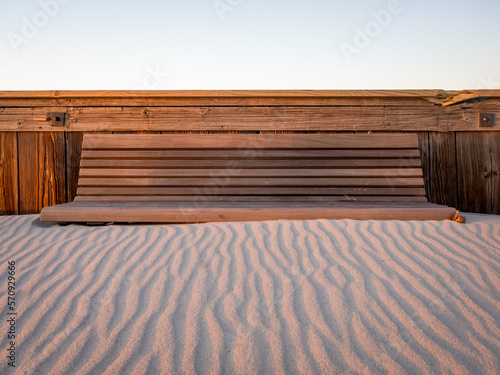 Wooden bench surrounded by beach sand in winter
