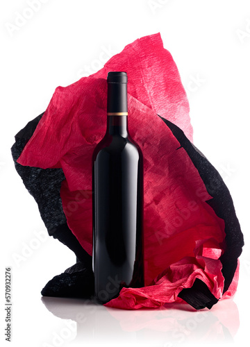 Bottle of red wine with crumpled crepe paper isolated on a white background.