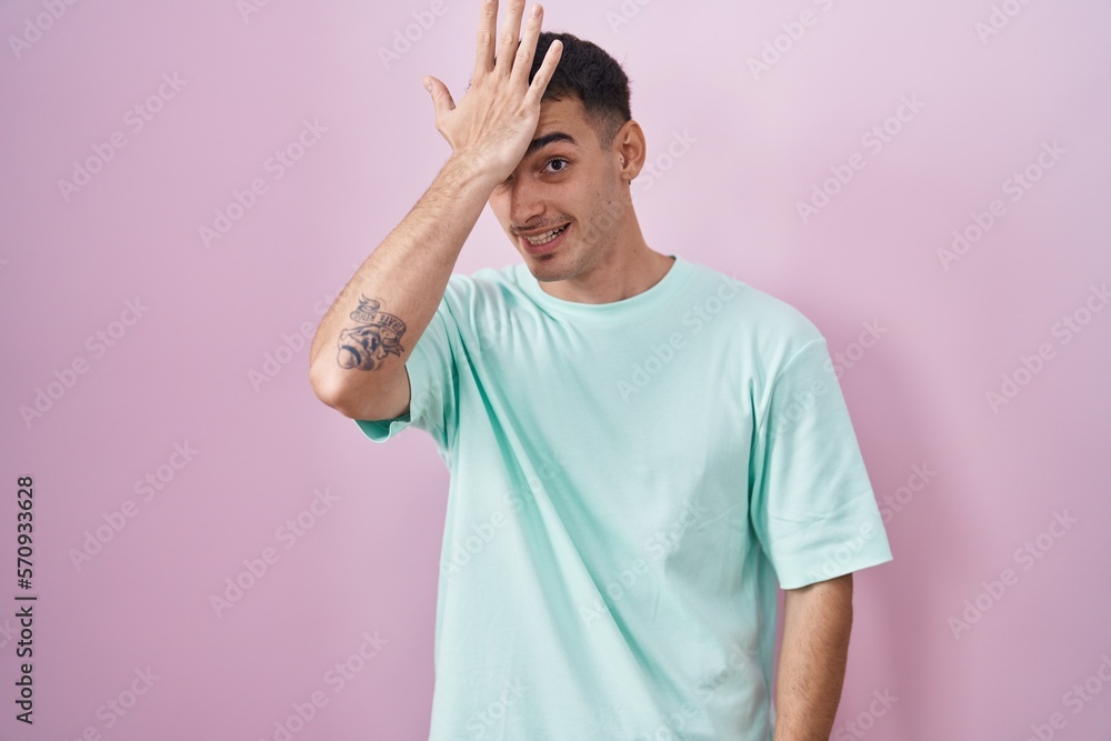 Handsome hispanic man standing over pink background surprised with hand on head for mistake, remember error. forgot, bad memory concept. Handsome hispanic man standing over pink background surprised with hand on head for mistake, remember error. forgot, bad memory concept.