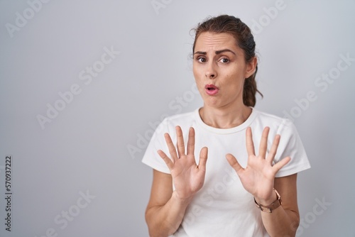 Billede på lærred Beautiful brunette woman standing over isolated background moving away hands palms showing refusal and denial with afraid and disgusting expression