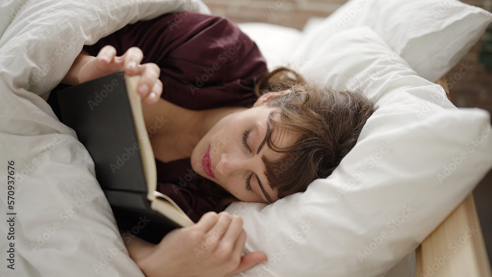 Young caucasian woman reading a book in the bed at bedroom