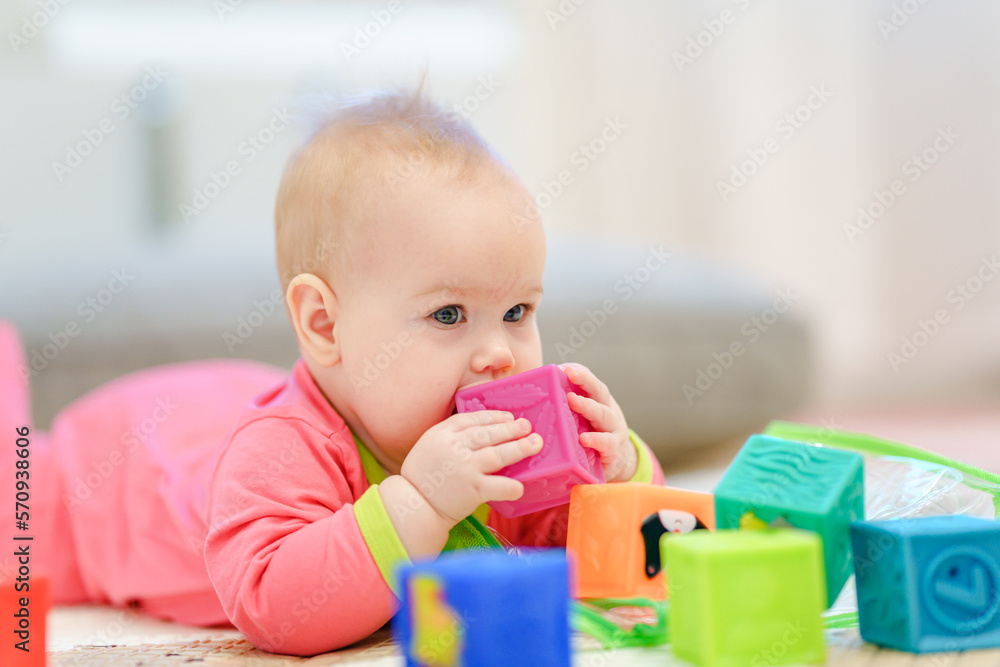 A cute little baby is lying on his stomach and playing cubes A cute little baby is lying on his stomach and playing cubes