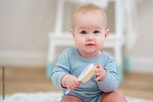 Little cute toddler baby is playing with a comb. Portrait of a child