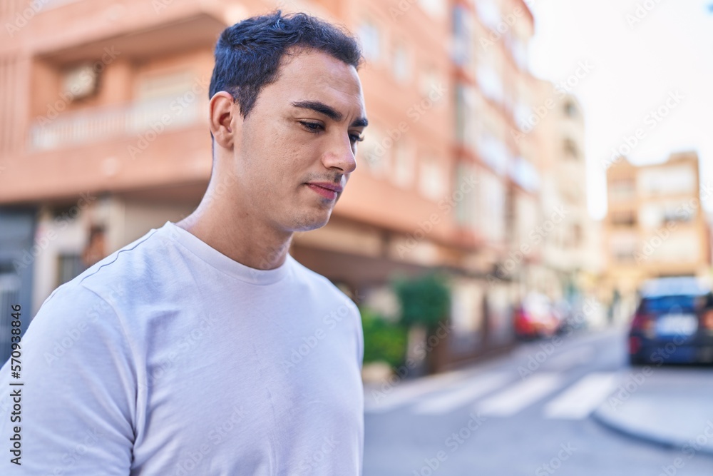 Young hispanic man looking to the side with serious expression at street Young hispanic man looking to the side with serious expression at street
