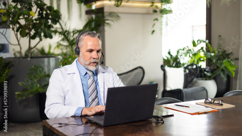 Senior caucasian doctor online video call conference consult patient with headset on laptop computer. Doctor online consultation and telehealth medicine
