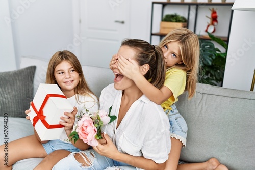 Mother and daughters smiling confident suprise with gift and flowers at home