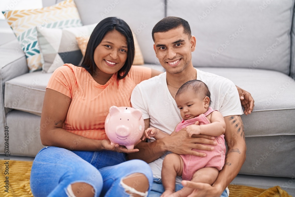 Young hispanic couple with baby holding piggy bank smiling with a happy and cool smile on face. showing teeth. Young hispanic couple with baby holding piggy bank smiling with a happy and cool smile on face. showing teeth.
