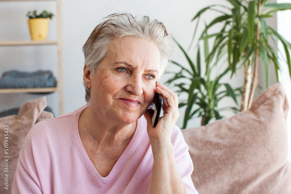 Mature woman sitting on sofa at home with mobile phone Mature woman sitting on sofa at home with mobile phone