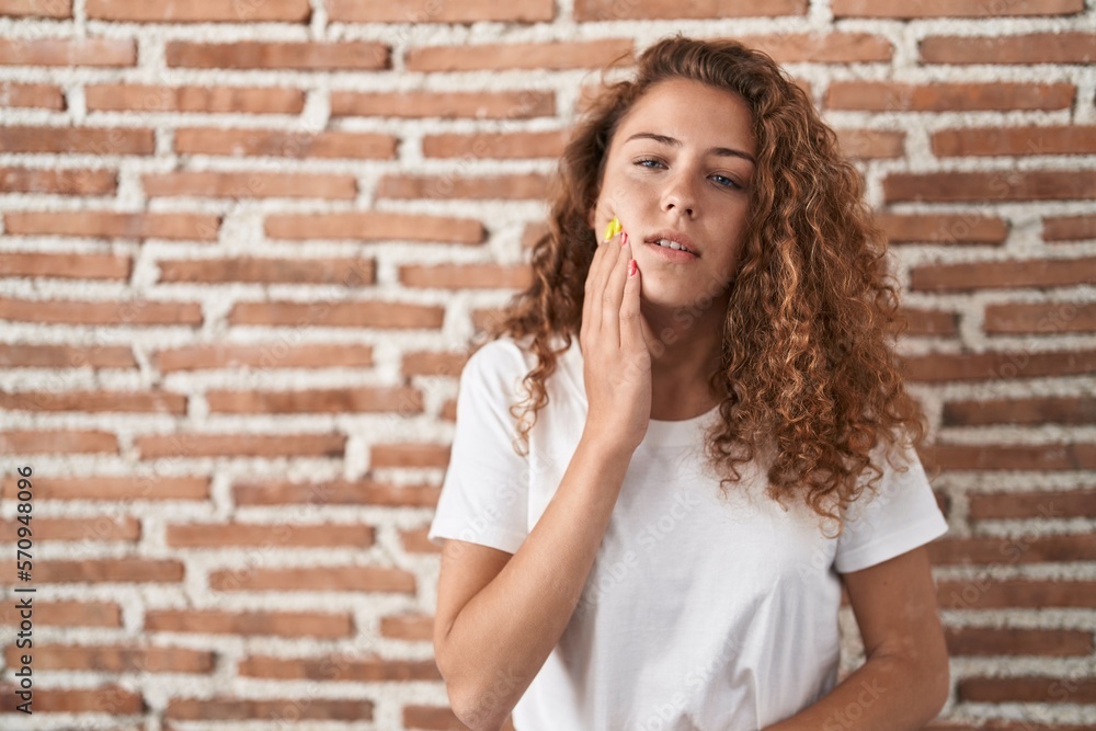 Young caucasian woman standing over bricks wall background touching mouth with hand with painful expression because of toothache or dental illness on teeth. dentist Young caucasian woman standing over bricks wall background touching mouth with hand with painful expression because of toothache or dental illness on teeth. dentist