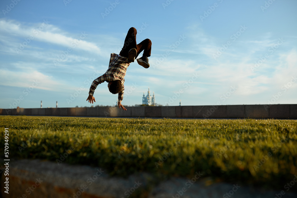 Back view of boy flying in air upside down during his back flip trick