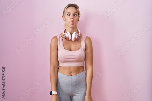 Vászonkép Young blonde woman wearing sportswear and headphones making fish face with lips, crazy and comical gesture