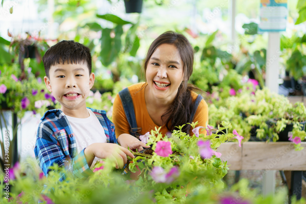 Happy Asian woman and little boy planting a house plants in green house together. Happy Asian woman and little boy planting a house plants in green house together.