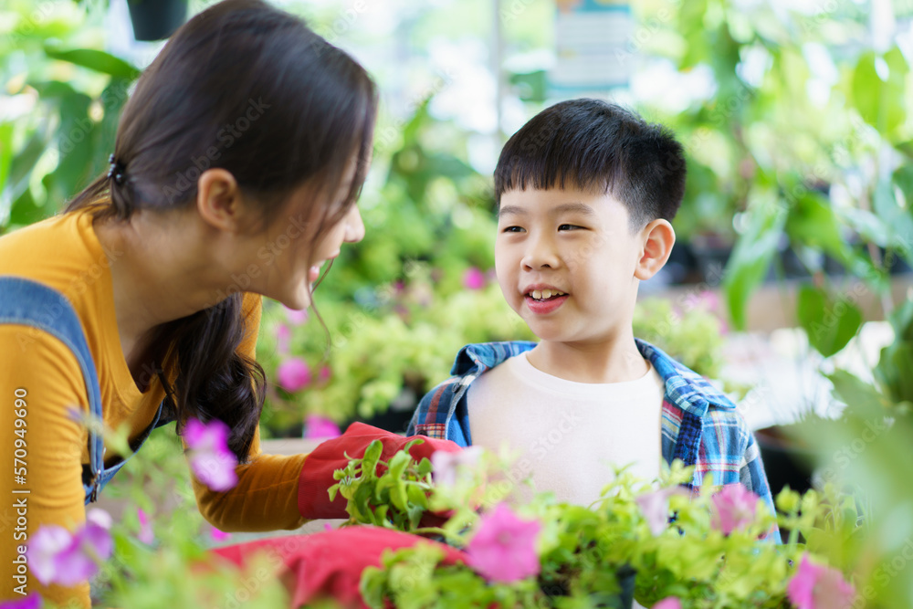 Obraz premium Happy Asian woman and little boy planting a house plants in green house together. 