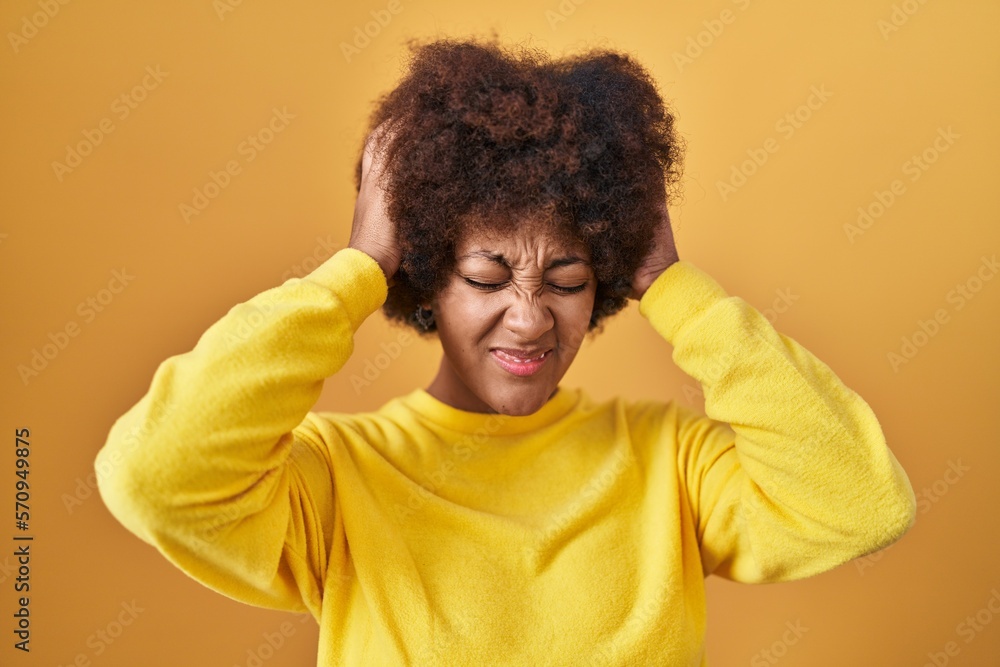 Young african american woman standing over yellow background suffering from headache desperate and stressed because pain and migraine. hands on head. Young african american woman standing over yellow background suffering from headache desperate and stressed because pain and migraine. hands on head.
