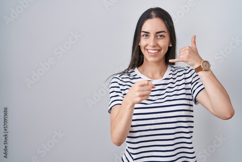 Wallpaper Mural Young brunette woman wearing striped t shirt smiling doing talking on the telephone gesture and pointing to you. call me. Torontodigital.ca