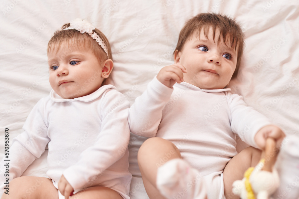 Two adorable babies lying on bed at bedroom Two adorable babies lying on bed at bedroom