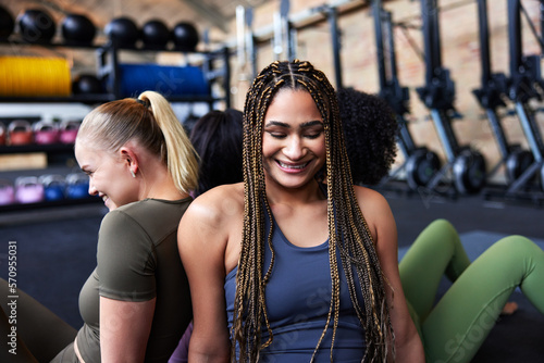 Diverse young female friends laughing at the gym. People in gym exercising. photo