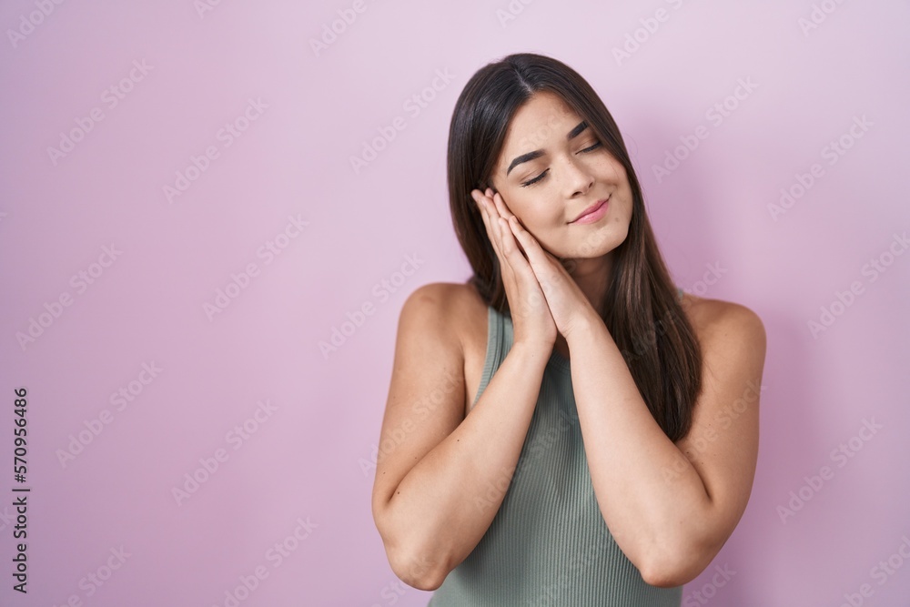 Hispanic woman standing over pink background sleeping tired dreaming and posing with hands together while smiling with closed eyes. Hispanic woman standing over pink background sleeping tired dreaming and posing with hands together while smiling with closed eyes.