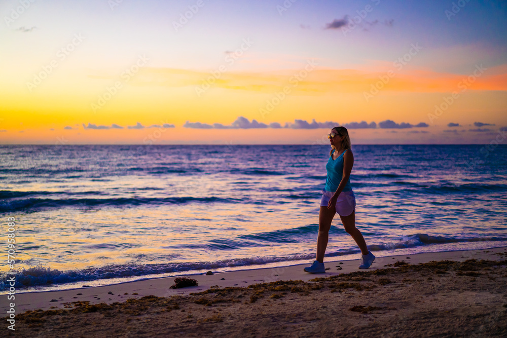 Beach holiday - beautiful woman walking on sunny, tropical beach 