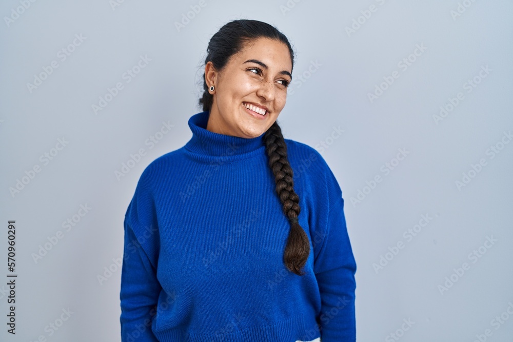 Young hispanic woman standing over isolated background looking away to side with smile on face, natural expression. laughing confident. Young hispanic woman standing over isolated background looking away to side with smile on face, natural expression. laughing confident.