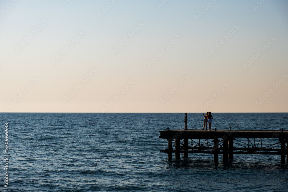 Silhouettes of people on a derelict pier