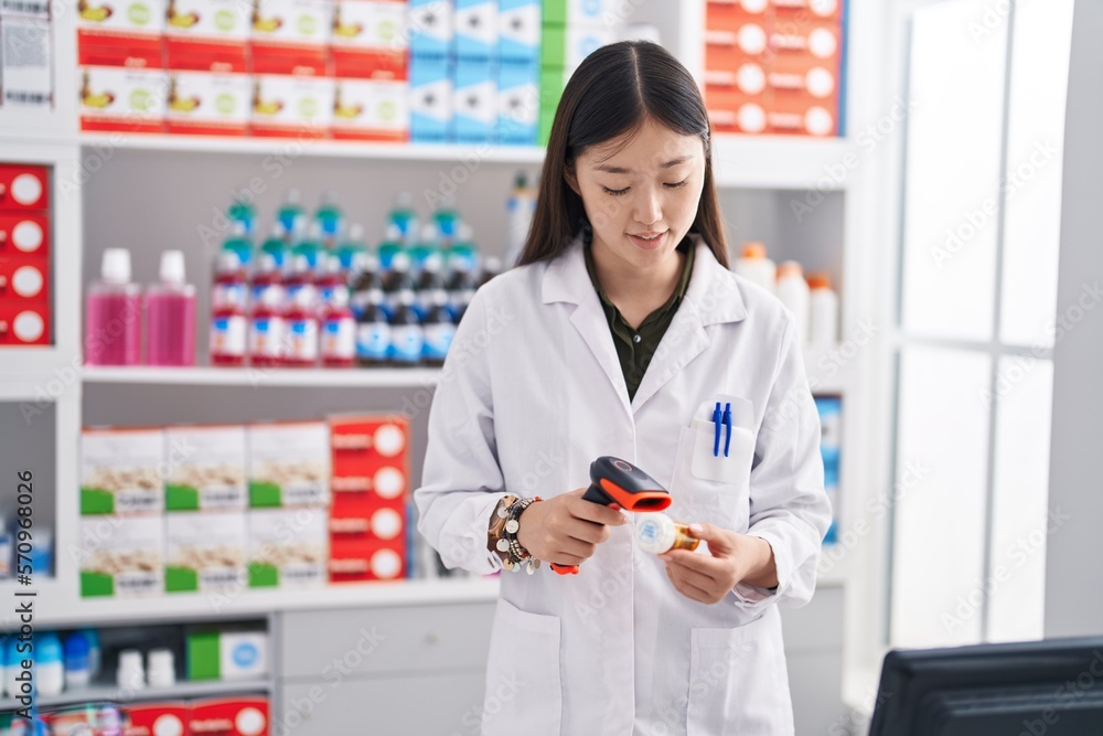 Chinese woman pharmacist scanning pills bottle at pharmacy