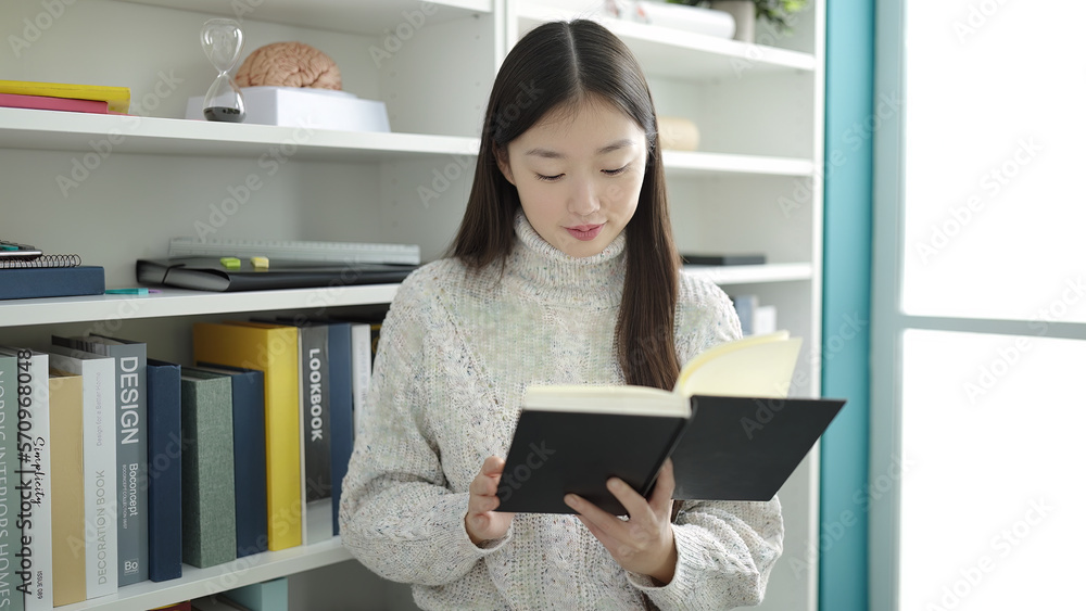 Young chinese woman student reading book studying at library university Young chinese woman student reading book studying at library university