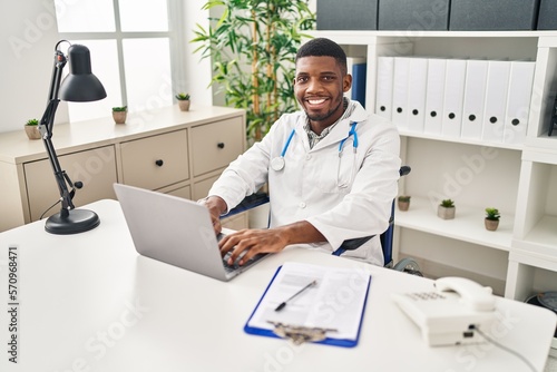 Young african american man wearing doctor uniform sitting on wheelchair working at clinic