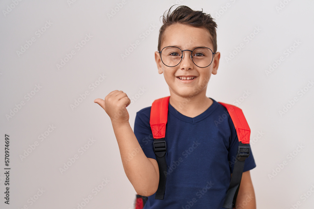Little hispanic boy wearing glasses and student backpack pointing thumb up to the side smiling happy with open mouth Little hispanic boy wearing glasses and student backpack pointing thumb up to the side smiling happy with open mouth