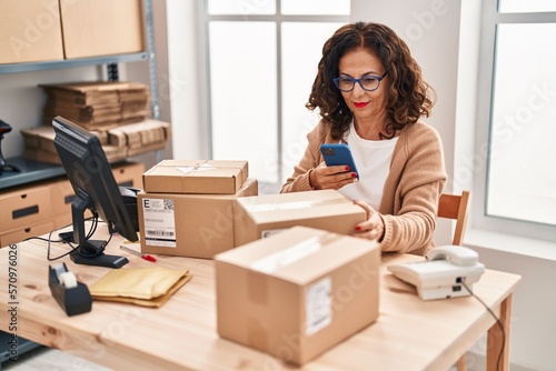Middle age hispanic woman working with parcels at ecommerce