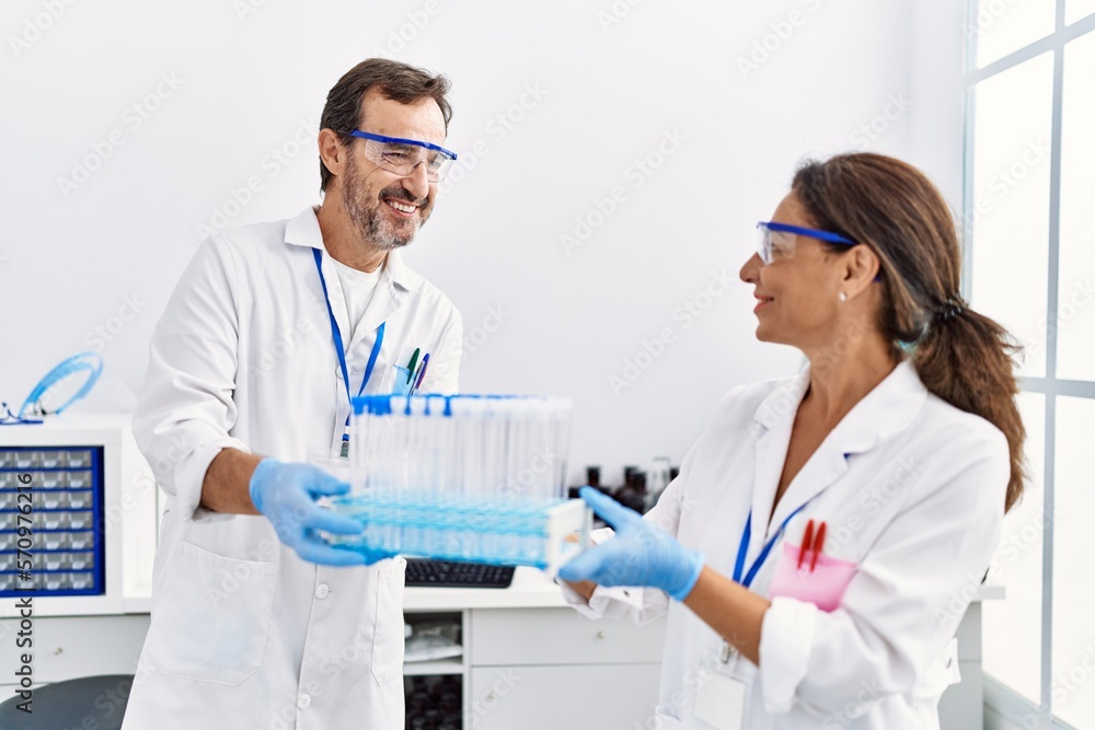Middle age man and woman partners wearing scientist uniform holding test tube at laboratory Middle age man and woman partners wearing scientist uniform holding test tube at laboratory