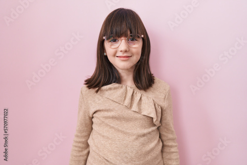 Little hispanic girl wearing glasses looking positive and happy standing and smiling with a confident smile showing teeth