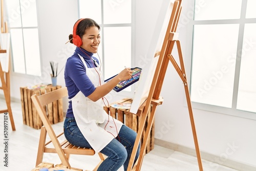 Young latin woman listening to music drawing at art studio