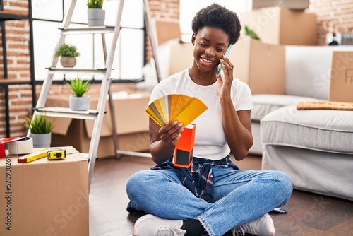 African american woman talking on the smartphone choose paint color at new home