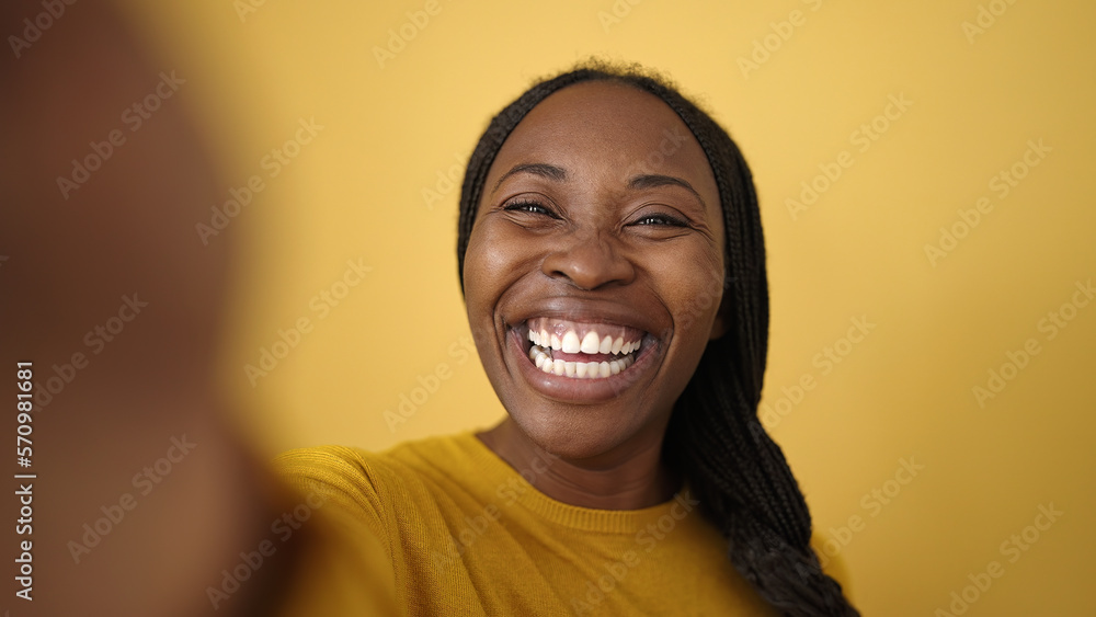 African woman taking selfie smiling over isolated yellow background African woman taking selfie smiling over isolated yellow background