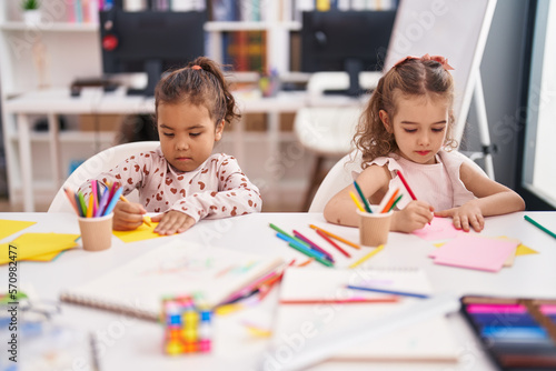 Two kids preschool students sitting on table drawing on paper at classroom