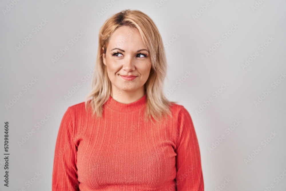 Blonde woman standing over isolated background smiling looking to the side and staring away thinking. Blonde woman standing over isolated background smiling looking to the side and staring away thinking.