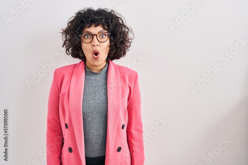 Hispanic woman with curly hair standing over isolated background afraid and shocked with surprise expression, fear and excited face.