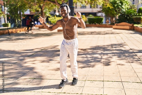 African american woman shirtless listening to music and dancing at park
