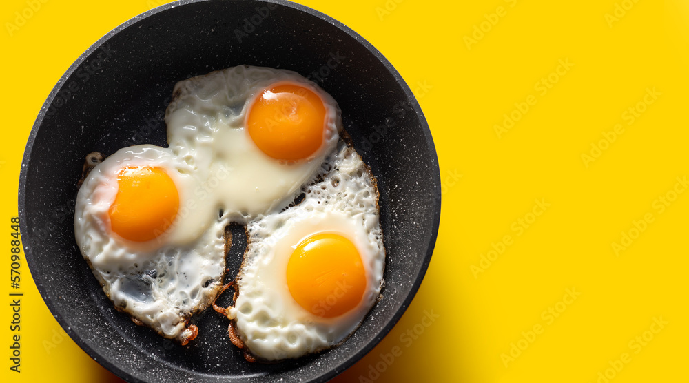 Frying pan with scrambled eggs from 3 eggs on a yellow background Frying pan with scrambled eggs from 3 eggs on a yellow background