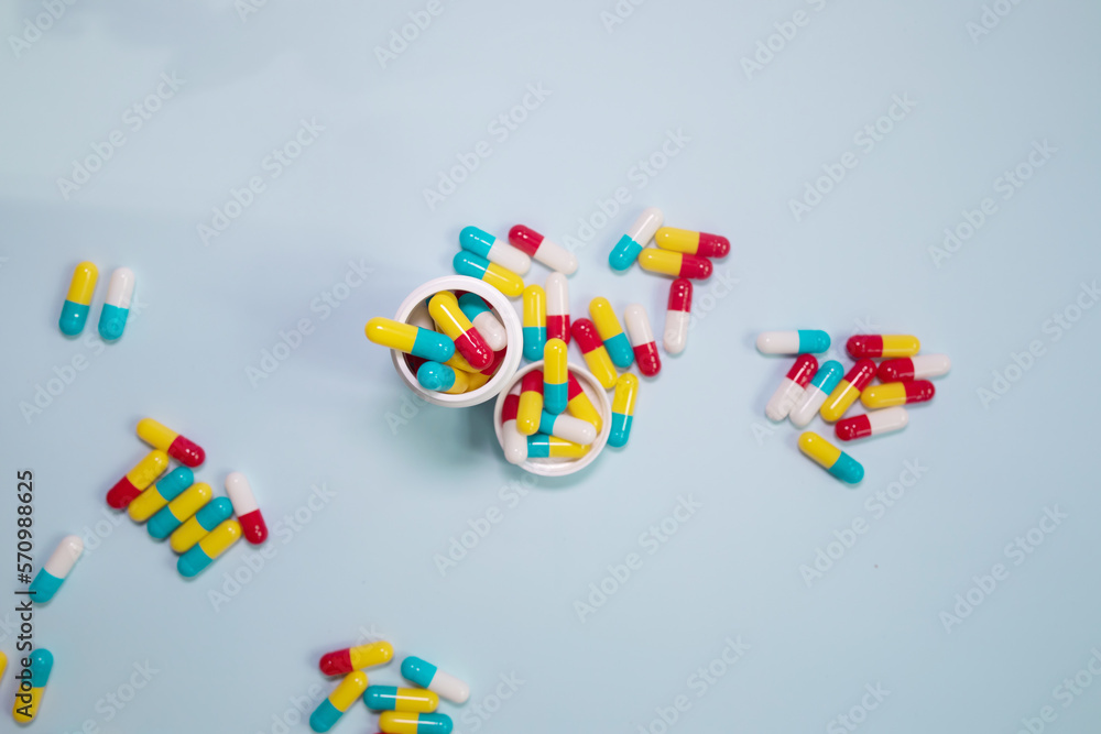 Pills spilling out of pill bottle and isolated on blue. Top view with copy space. Medicine concept. Pills spilling out of pill bottle and isolated on blue. Top view with copy space. Medicine concept.