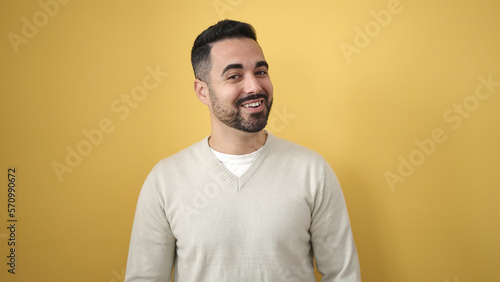 Young hispanic man smiling confident standing over isolated yellow background