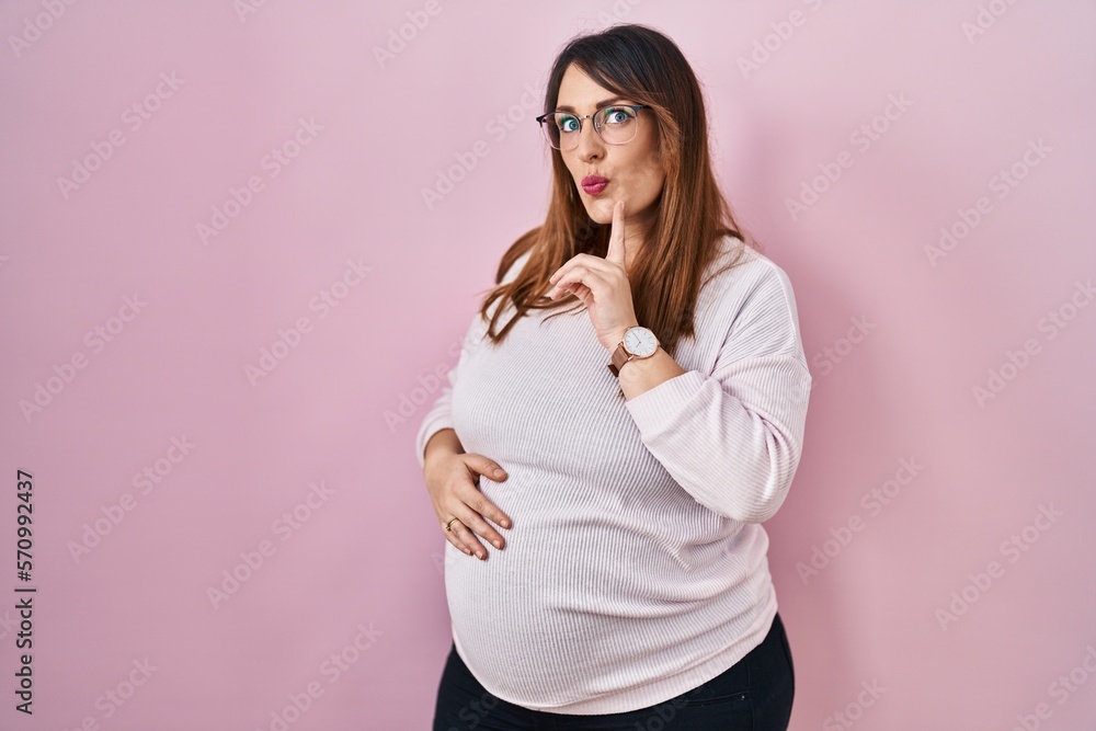 Pregnant woman standing over pink background thinking concentrated about doubt with finger on chin and looking up wondering Pregnant woman standing over pink background thinking concentrated about doubt with finger on chin and looking up wondering