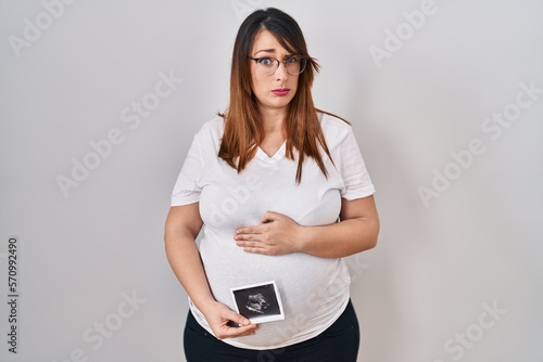Pregnant woman holding baby ecography skeptic and nervous, frowning upset because of problem. negative person.