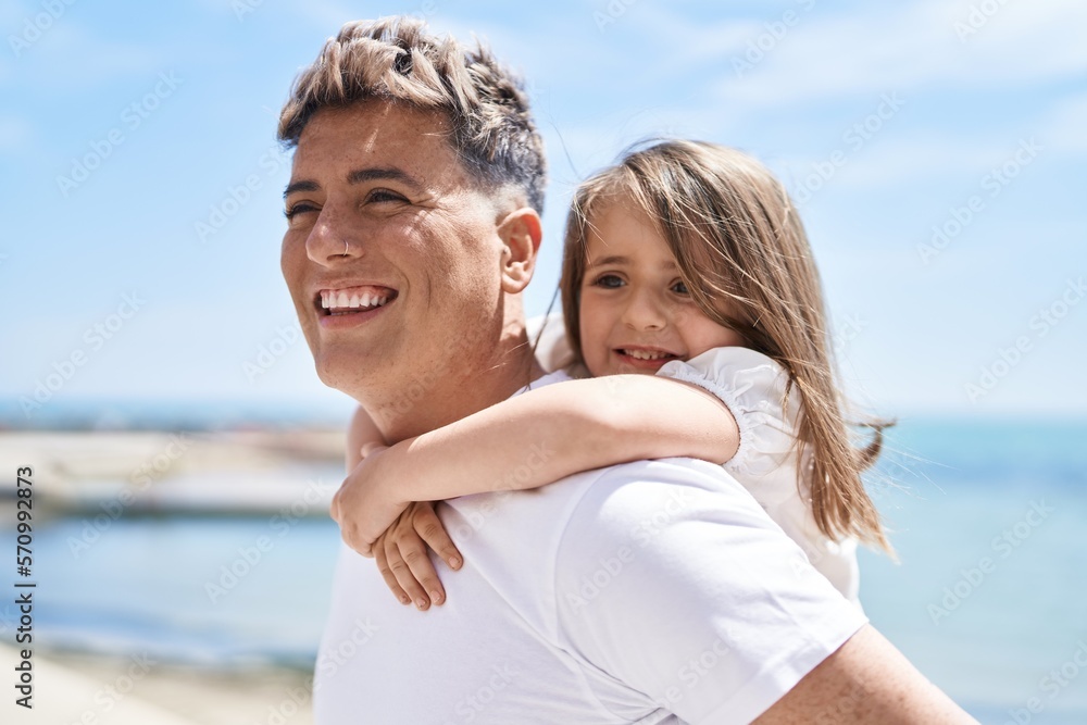 Father and daughter smiling confident hugging each other holding on back at seaside Father and daughter smiling confident hugging each other holding on back at seaside