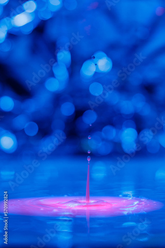 A drop falls into a thick liquid with a blue-pink background. Abstract colorful background.